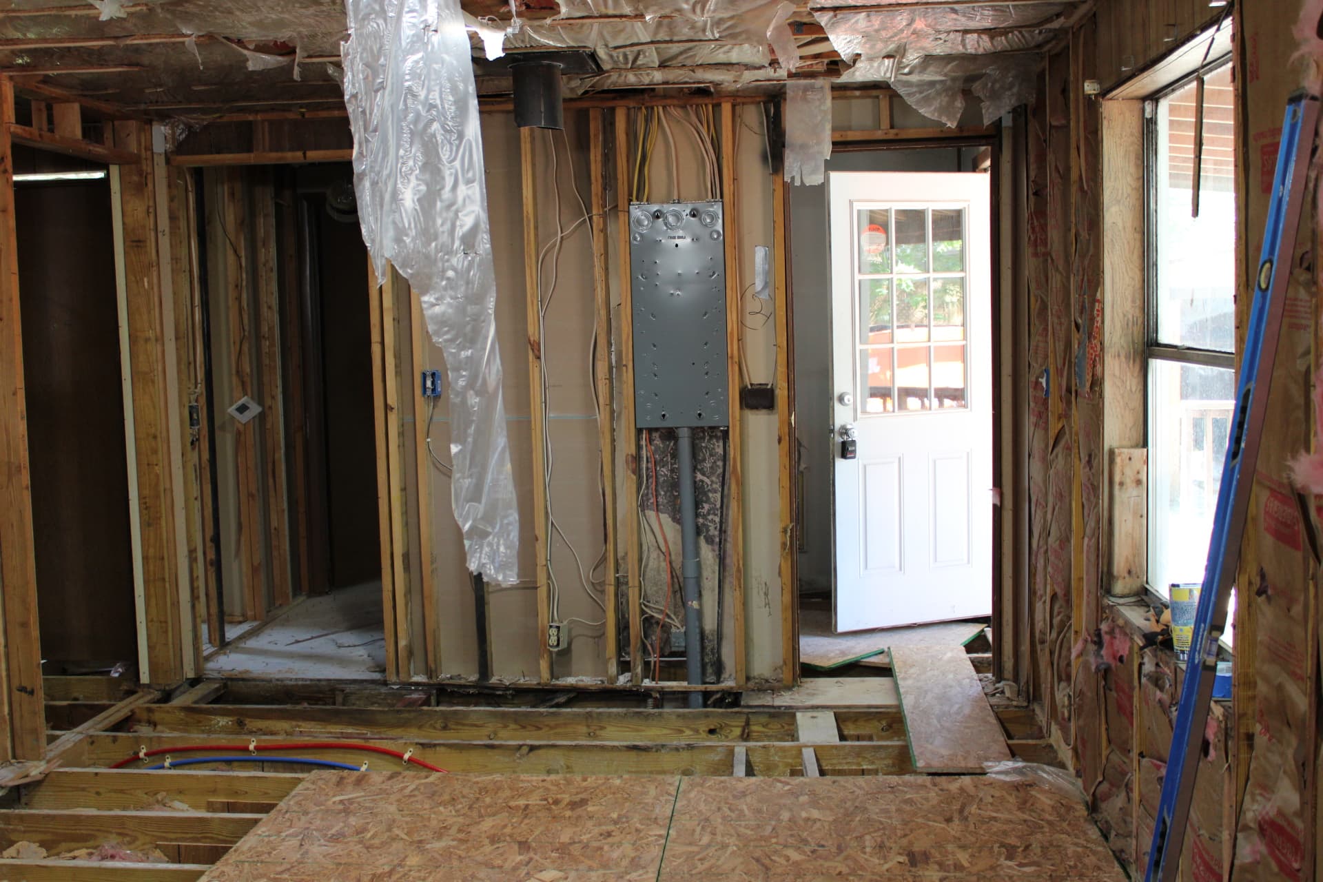 Electrical panel, wall framing, and open subfloor during renovation